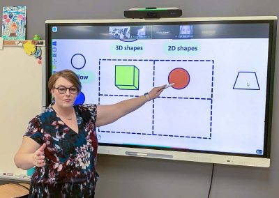 woman teaching on classroom smart board